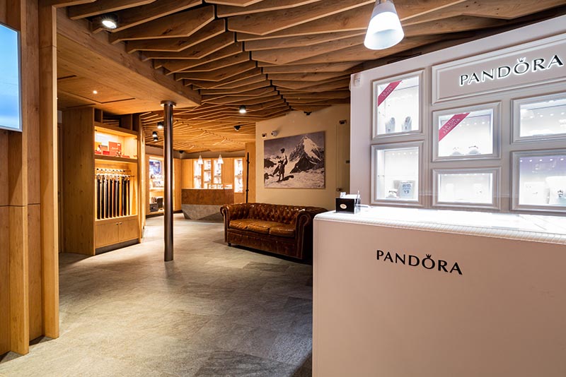 Interno di un negozio elegante con vetrine illuminate e soffitto in legno.